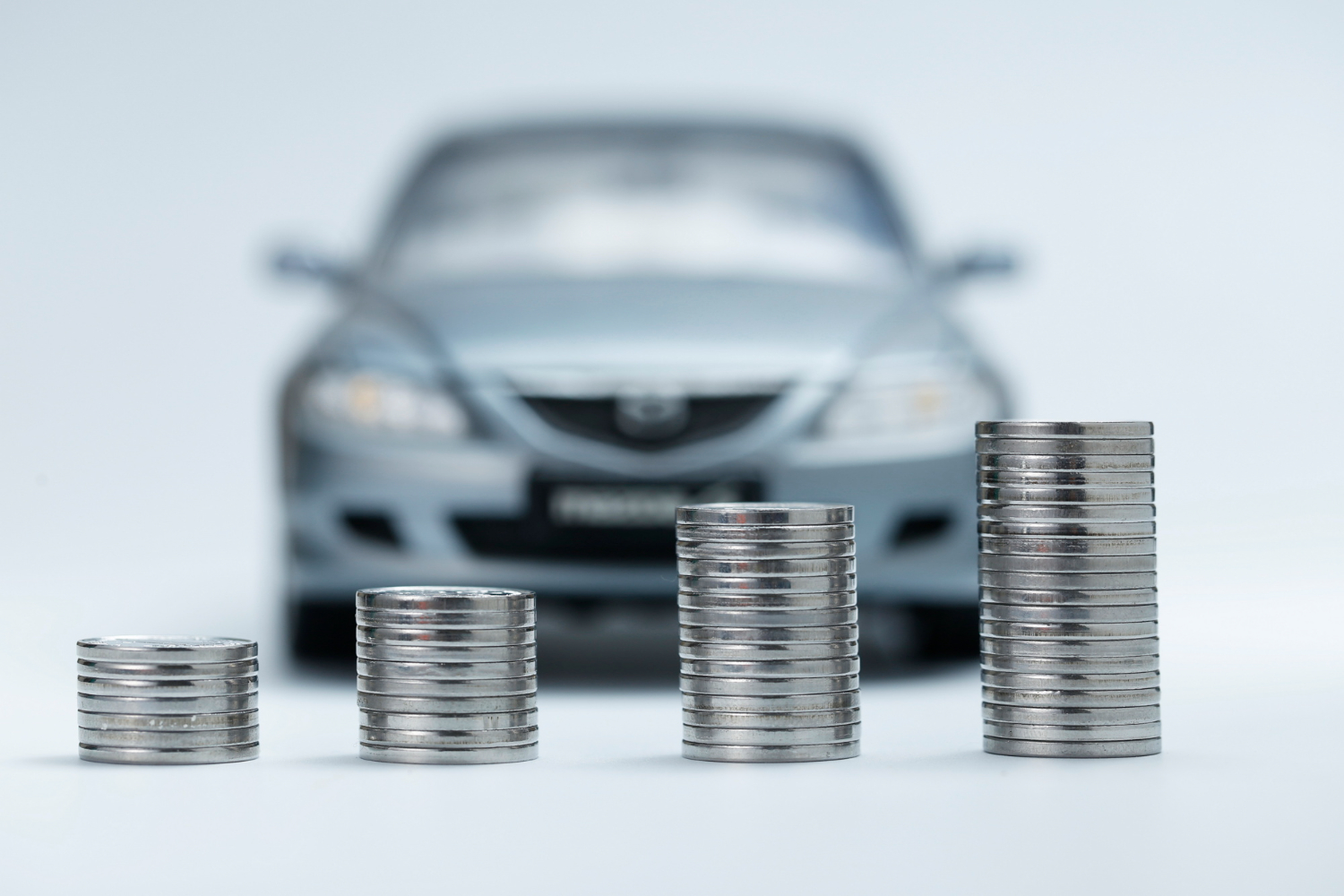 Novčići poređani u nizovima ispred automobila, ilustracija troškova najma